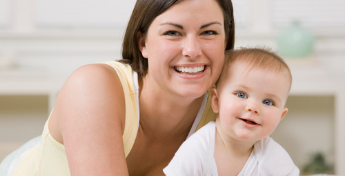 A young woman smiling with her baby